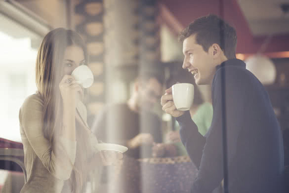 Two couples shot through window enjoying coffee